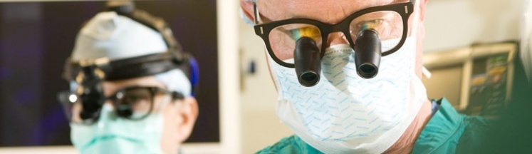 Two doctors wearing surgical magnifying glasses