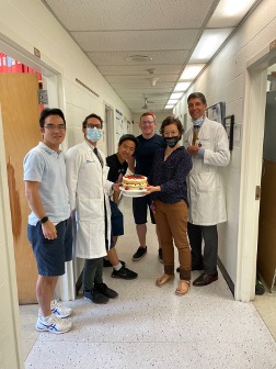 Group in hallway with farewell cake for Miriam (2021. 7)