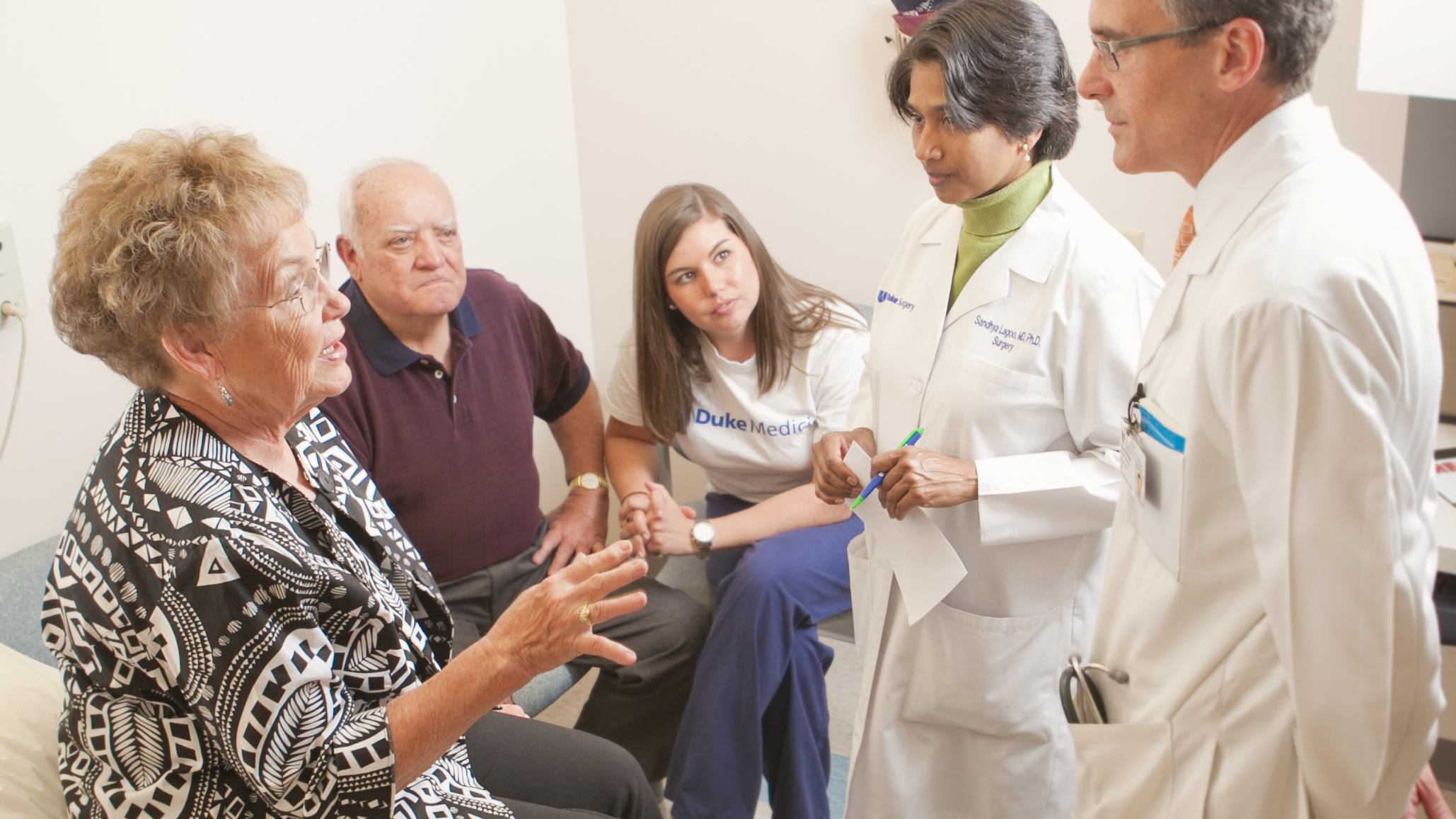 Photo of Dr. Lagoo-Deenadayalan and a colleague talking with an elderly patient and her family