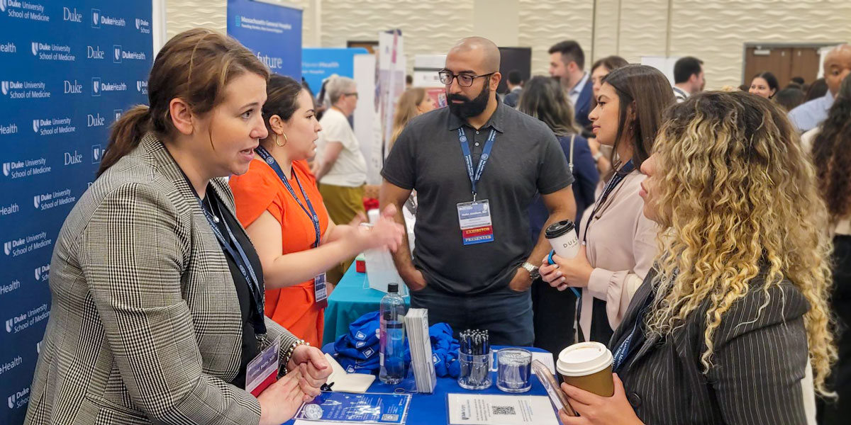 Photo of residents and faculty talking with medical students at an event booth