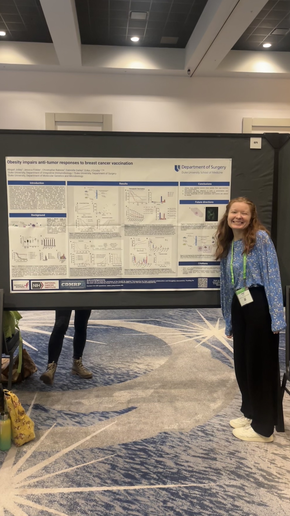 A woman stands smiling in front of her scientific research poster