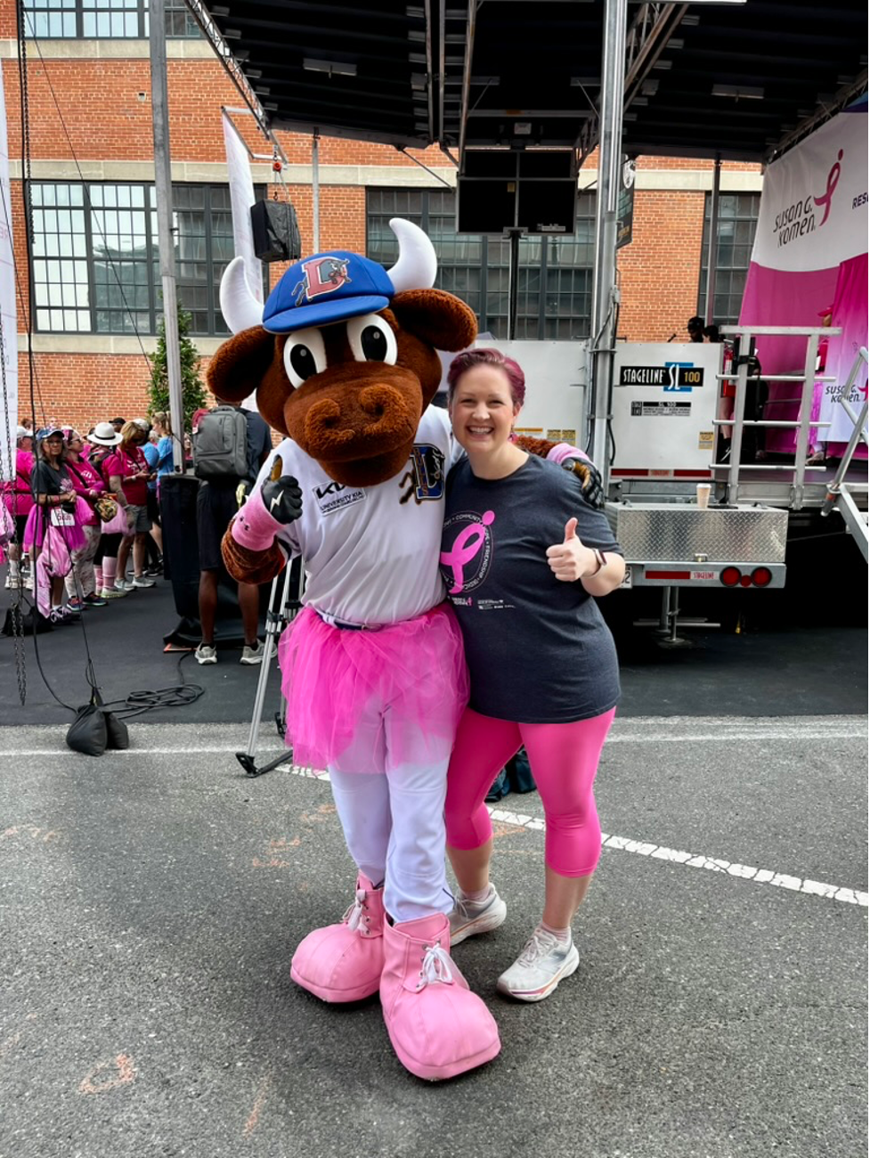 The Durham Bulls mascot and Dr. Erika Crosby pose together dressed in pink for breast cancer awareness, at the Komen Race for the Cure in Durham