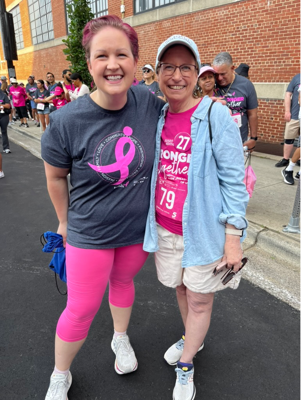 Two women dressed in pink pose together at the Susan G. Komen Race for the Cure in Downtown Durham