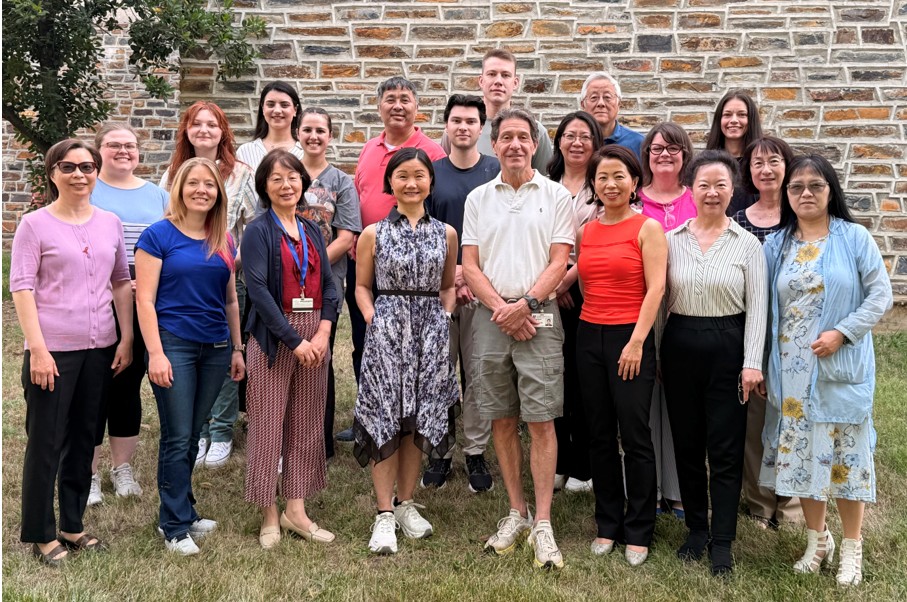 A group of people dressed in business casual gather for a group photo in front of a brick wall