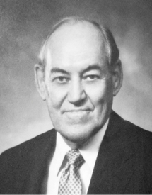 Black and white photo of Dr. William Shingleton wearing a black suit and tie