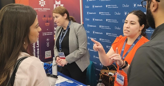 Individuals talk next to a booth at the LMSA national conference