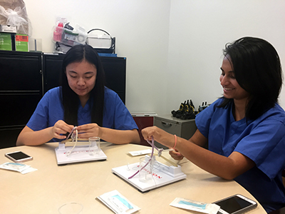 Undergraduate students Vivan Qi and Surabhi Beriwal practicing surgical knot tying