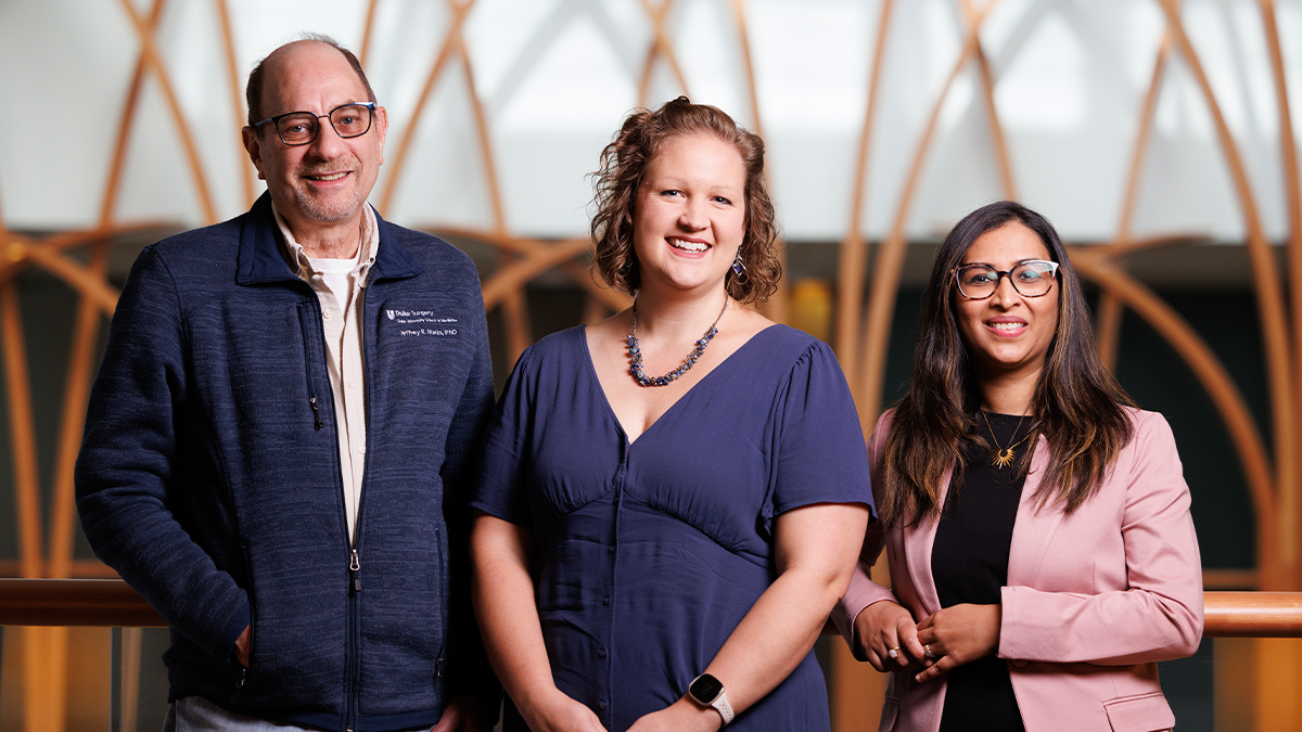 Three individuals pose smiling for a photo