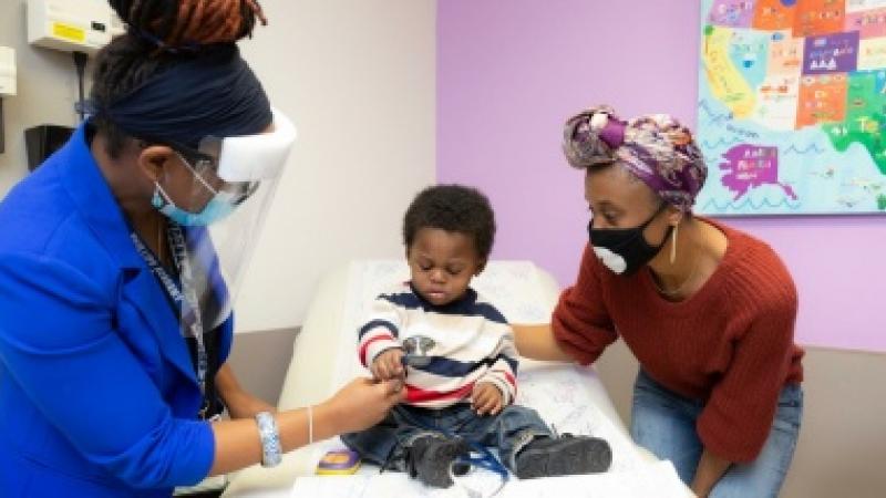 Gillian Noel, MD, shows her stethoscope to liver transplant patient, Noah Mann, as his mother, Talisha Becton (right), looks on