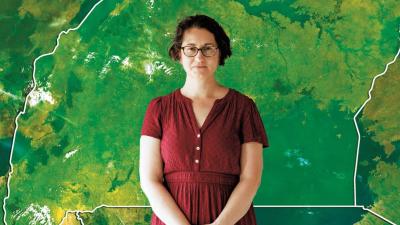 Dr. Tamara Fitzgerald stands in front of a green outline map of Uganda