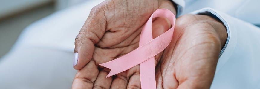 Hands holding a pink breast cancer awareness ribbon