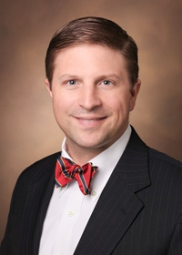 Dr. Alexander Hawkins in a professional headshot wearing a bowtie and his white coat