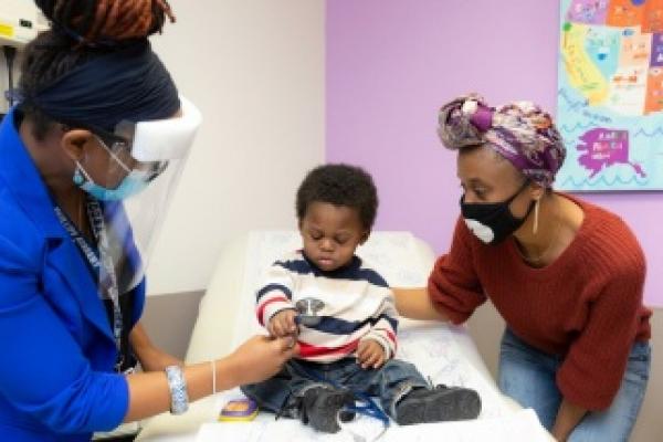 Gillian Noel, MD, shows her stethoscope to liver transplant patient, Noah Mann, as his mother, Talisha Becton (right), looks on
