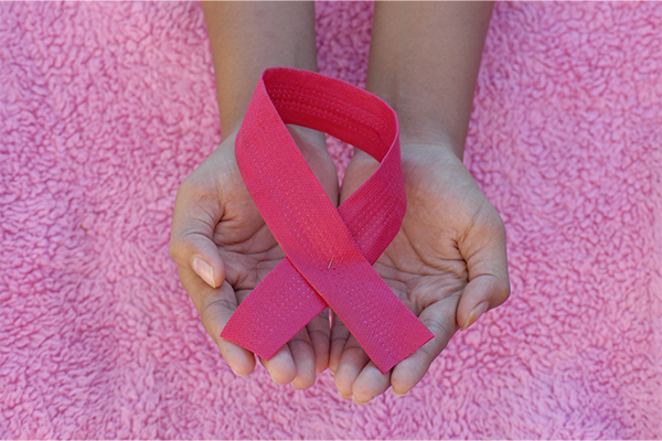 Hands holding a pink ribbon for Breast Cancer Awareness
