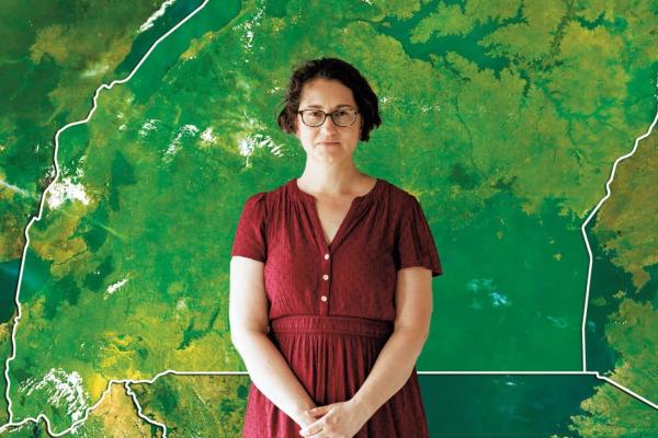 Dr. Tamara Fitzgerald stands in front of a green outline map of Uganda