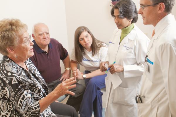 Photo of Dr. Lagoo-Deenadayalan and a colleague talking with an elderly patient and her family