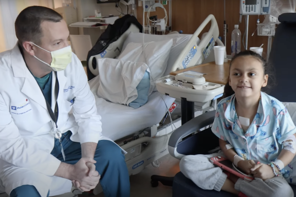 Dr. Doug Overbey sits in a hospital room with his patient, Kensley