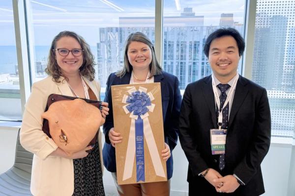 Three individuals stand with awards
