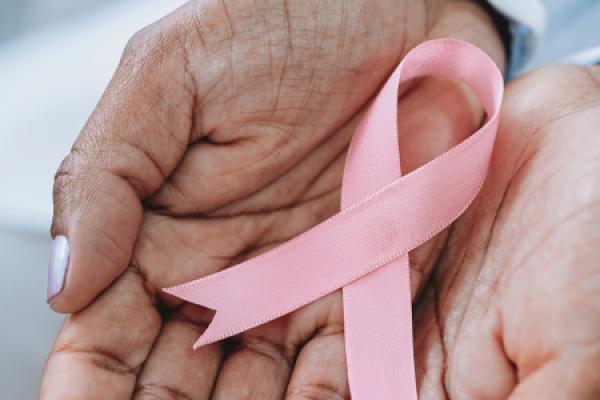 Hands holding a pink breast cancer awareness ribbon