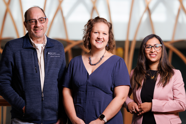 Three individuals pose smiling for a photo