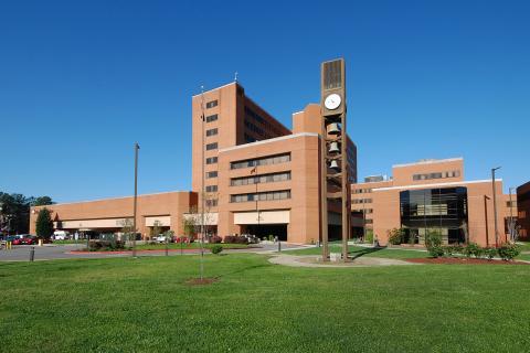front of the Durham VA health care system building, in front of a blue sky and green lawn