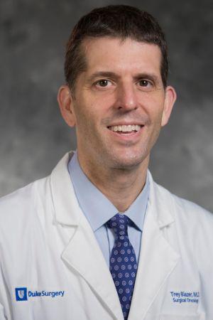 Professional photo of Dr. Trey Blazer, wearing his white coat and against a grey background