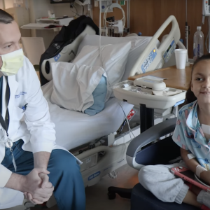 Dr. Doug Overbey sits in a hospital room with his patient, Kensley