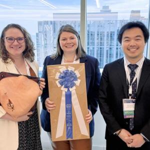 Three individuals stand with awards